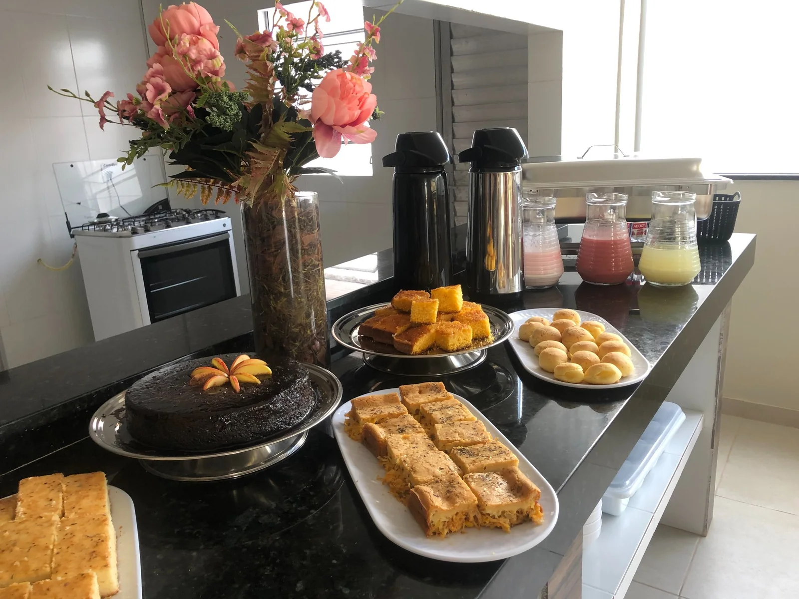 Mesa de café da manhã com bolos, pães, café e sucos